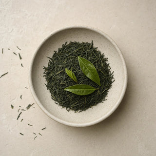 Loose Japanese sencha and fresh green tea leaves in a cream ceramic dish